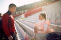 Young woman and man are chatting on the grandstand after a training at the stadium. Sport, athletics, athletes Royalty Free Stock Photo