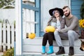 Young woman and man, family, sitting on porch of village house with pumpkins. Royalty Free Stock Photo