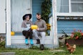 Young woman and man, family, sitting on porch of village house with pumpkins. Royalty Free Stock Photo