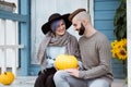 Young woman and man, family, sitting on porch of village house with pumpkins. Royalty Free Stock Photo