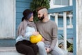 Young woman and man, family, sitting on porch of village house with pumpkins. Royalty Free Stock Photo