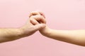 young woman and man holding hands together on pink background. Royalty Free Stock Photo