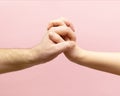 young woman and man holding hands together on pink background. Royalty Free Stock Photo