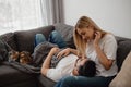Young woman and man relaxing at a sofa in the living room at their home, cat sitting nearby Royalty Free Stock Photo