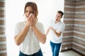 Young woman and man in room during quarantine. Guy scream at his wife. She crying and hold white tissue on cheek Royalty Free Stock Photo