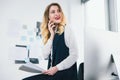 Young woman manager holding documents in her hands, looks busy while having phone conversation with business partner, multitasking Royalty Free Stock Photo