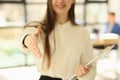 Young woman manager offers her hand for handshake in office.