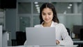 Young woman manager sitting in office looking at laptop screen receiving notification reads good news rejoices in Royalty Free Stock Photo