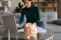 Young woman managing household budget at home office using laptop