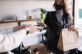 Young woman in mask paying bill through smartphone using NFC technology in a cafe. Female customer paying using Royalty Free Stock Photo