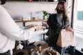 Young woman in mask paying bill through smartphone using NFC technology in a cafe. Female customer paying using Royalty Free Stock Photo