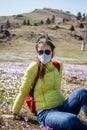 Young woman in mask and sunglasses walking outside