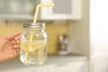 Young woman with mason jar of lemon water in kitchen. Space for text Royalty Free Stock Photo