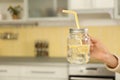 Young woman with mason jar of lemon water in kitchen. Space for text Royalty Free Stock Photo