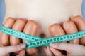 A young woman measures her slim waist with sausages Royalty Free Stock Photo