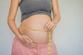 Young woman measuring her pregnant belly with centimeter tape. Centimeters European standard. Preparation for childbirth Royalty Free Stock Photo