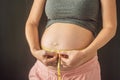 Young woman measuring her pregnant belly with centimeter tape. Centimeters European standard. Preparation for childbirth Royalty Free Stock Photo