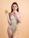 Young woman measuring waist. Weight loss for slim waist. Female model with slim waist holding apple and measuring tape Royalty Free Stock Photo