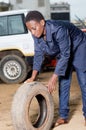 Young woman mechanic with a tire in car workshop Royalty Free Stock Photo