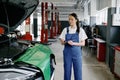 Young woman mechanic writing on clipboard at repair garage Royalty Free Stock Photo
