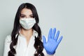 Young woman in medical face mask showing stop pandemic gesture. Woman in safety mask and medical gloves. Flu epidemic and virus