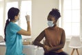 Young woman in medical face mask waiting for nurse to get syringe ready for injection Royalty Free Stock Photo