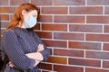 A young woman in a medical mask against a red brick wall, copy space for text Royalty Free Stock Photo