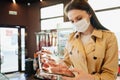 Young woman in medical mask buying raw meat in grocery store Royalty Free Stock Photo