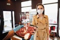 Young woman in medical mask buying raw meat in grocery store Royalty Free Stock Photo
