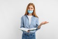 Young woman in a medical mask on her face, with books conducts training, on a white background