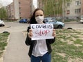 Young woman in medical mask holding sheet with inscription covid19 stop. Adult female protecting yourself from diseases