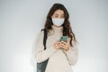 Young woman in medical mask looking down at her phone that she& x27;s holding Royalty Free Stock Photo