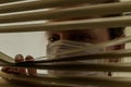 Young woman in medical mask looks out the window through the blinds Royalty Free Stock Photo