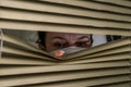 Young woman in medical mask looks out the window through the blinds Royalty Free Stock Photo