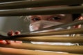 Young woman in medical mask looks out the window through the blinds Royalty Free Stock Photo