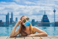 Young woman in medical mask in outdoor swimming pool with city view in blue sky Tourists fear the 2019-ncov virus Royalty Free Stock Photo