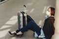Young woman in medical mask sits near luggage in airport. Tortured by the flight, the woman dozes Royalty Free Stock Photo