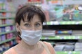 Young woman with a medical mask in a supermarket and looking at the camera. The concept of protection against coronavirus, and