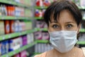 Young woman with a medical mask in a supermarket and looking at the camera. The concept of protection against coronavirus, and