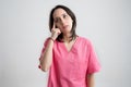 Young woman medical professional nurse or doctor dressed with pink hospital clothes wondering