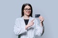 Young woman medical specialist, doctor holding bank credit card on gray background Royalty Free Stock Photo