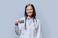 Young woman medical specialist, doctor holding bank credit card on gray background Royalty Free Stock Photo