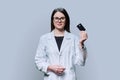 Young woman medical specialist, doctor holding bank credit card on gray background Royalty Free Stock Photo