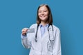 Young woman medical specialist, doctor holding bank credit card on blue background Royalty Free Stock Photo