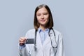 Young woman medical specialist, doctor holding bank credit card on gray background Royalty Free Stock Photo