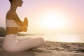 Young woman meditating on beach at sunrise, closeup. Practicing yoga Royalty Free Stock Photo