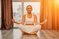 Young woman meditating at home. Girl practicing yoga in class. Relaxation at home, body care, balance, healthy lifestyle Royalty Free Stock Photo