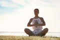 Young woman meditating near river at sunset, space for text. Nature healing power