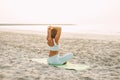 Young woman meditating in pose of lotus on beach near the sea at sunset in summer, rear view Royalty Free Stock Photo