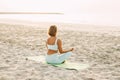 Young woman meditating in pose of lotus on beach near the sea at sunset in summer, rear view Royalty Free Stock Photo